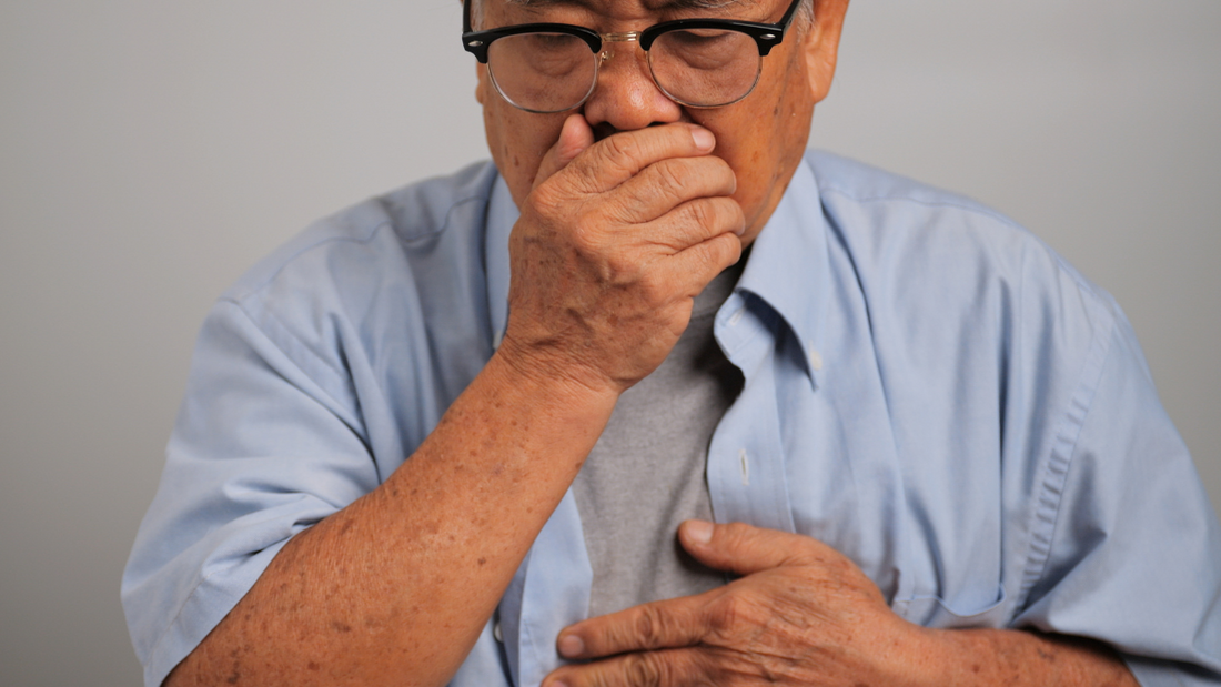 A man coughing and holding his chest