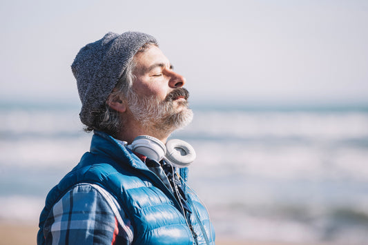 An older man standing on the beach breathing in