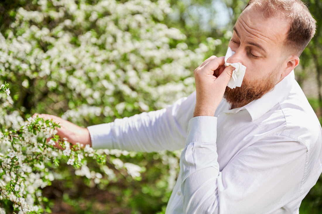A man sneezing near flowers