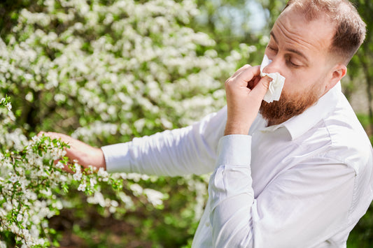 A man sneezing near flowers