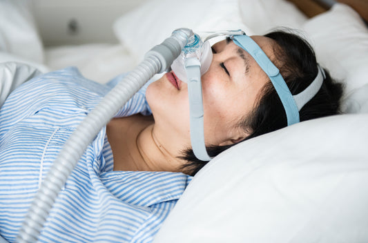 A person lying on a bed using a CPAP mask