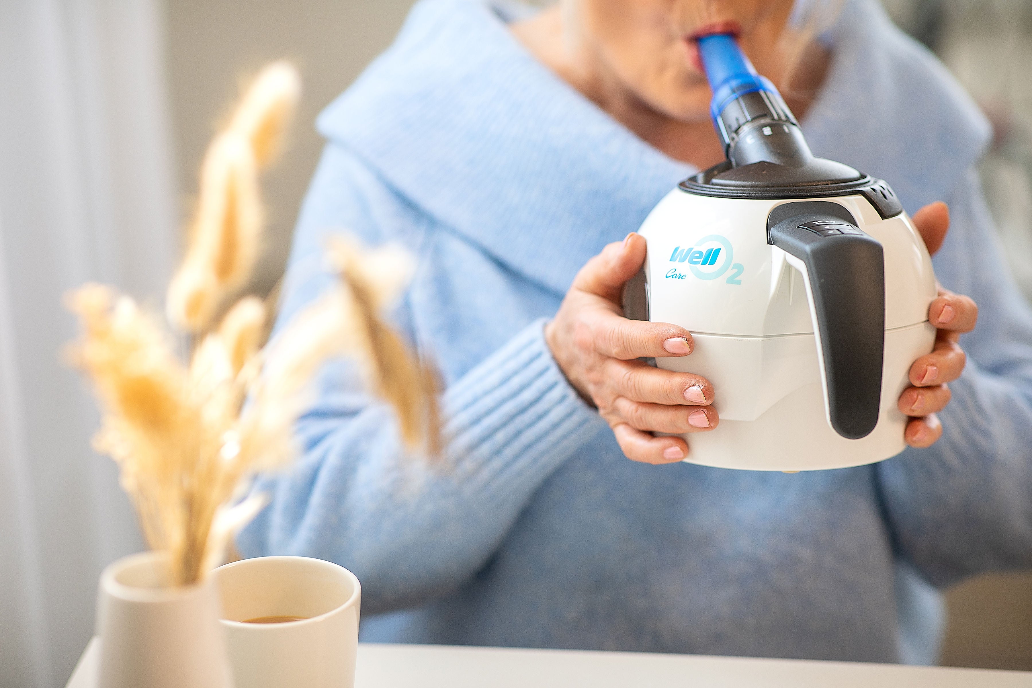 A woman breathing into the WellO2 device